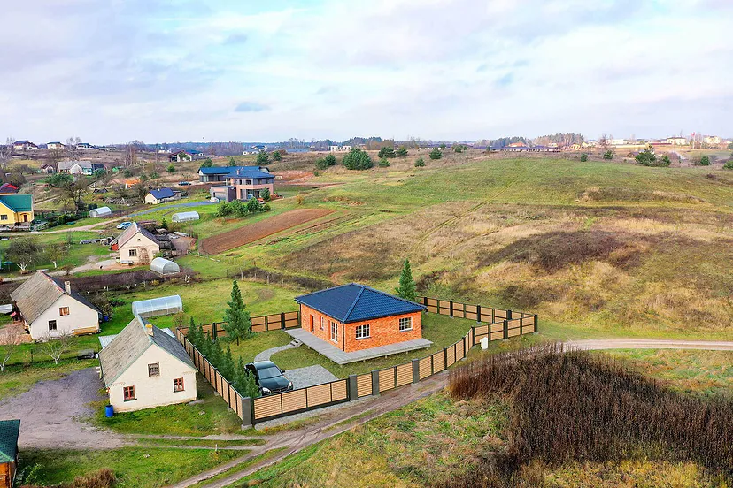 New house with a fence at the edge of a village, from the air