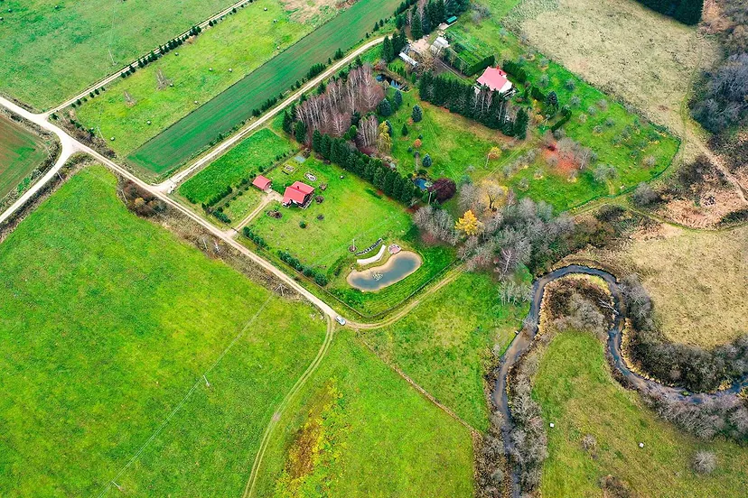 Homestead with a pond among fields and a stream, view from above