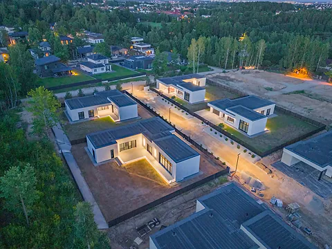 Neighborhood of single-story houses at dusk, outdoor lights on