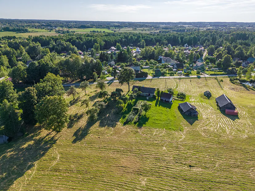 Homestead and a meadow being mowed in the evening light