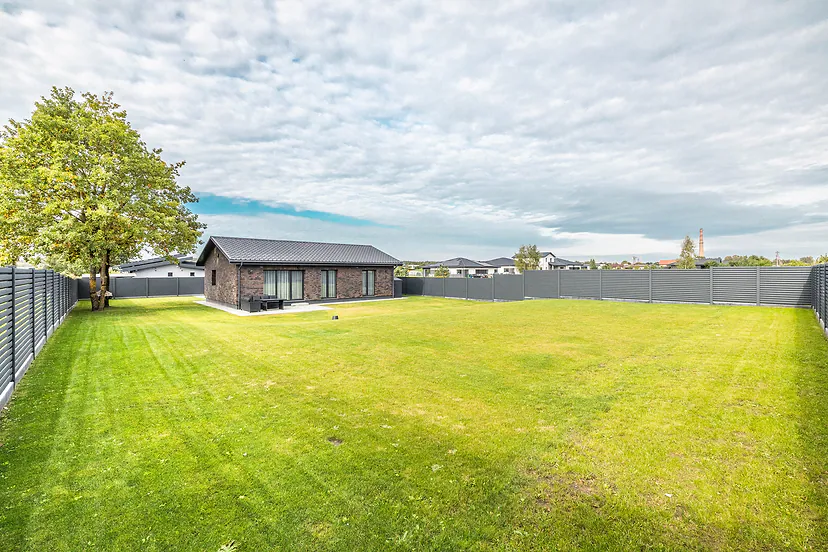 A large yard with a lawn, the house and the neighbors' houses beyond
