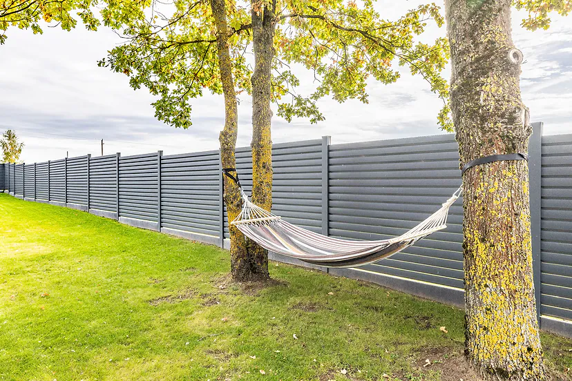 A hammock between the trees by the fence