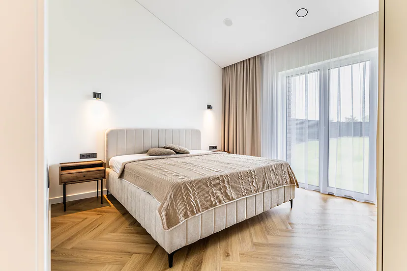 Bedroom with an upholstered bed and a large window facing the yard