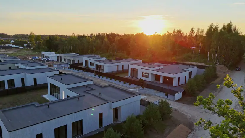Nauji vienaaukščiai namai iš oro nuo saulėlydžio iki tamsos, kai užsidega kiemų šviesos