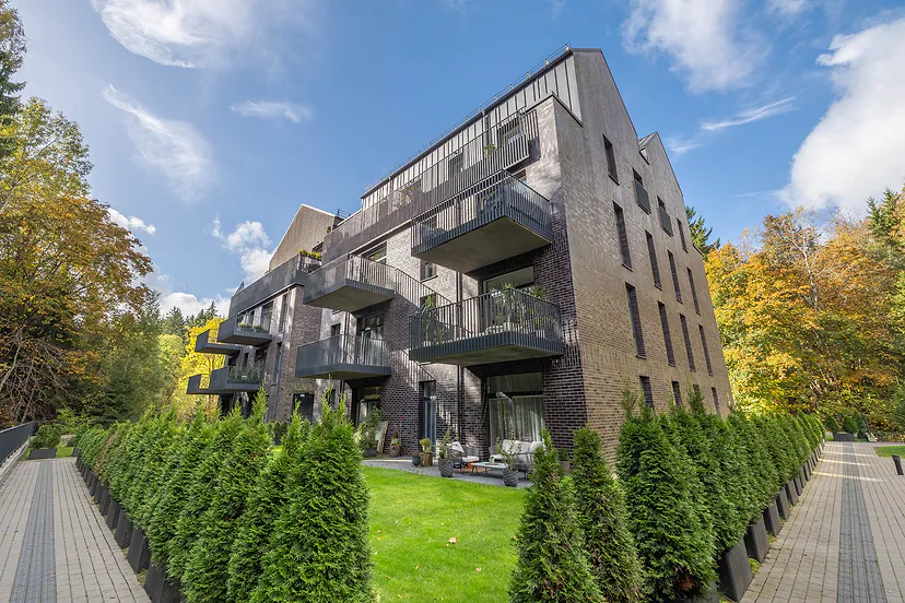 New dark brick apartment building with balconies, autumn trees around it