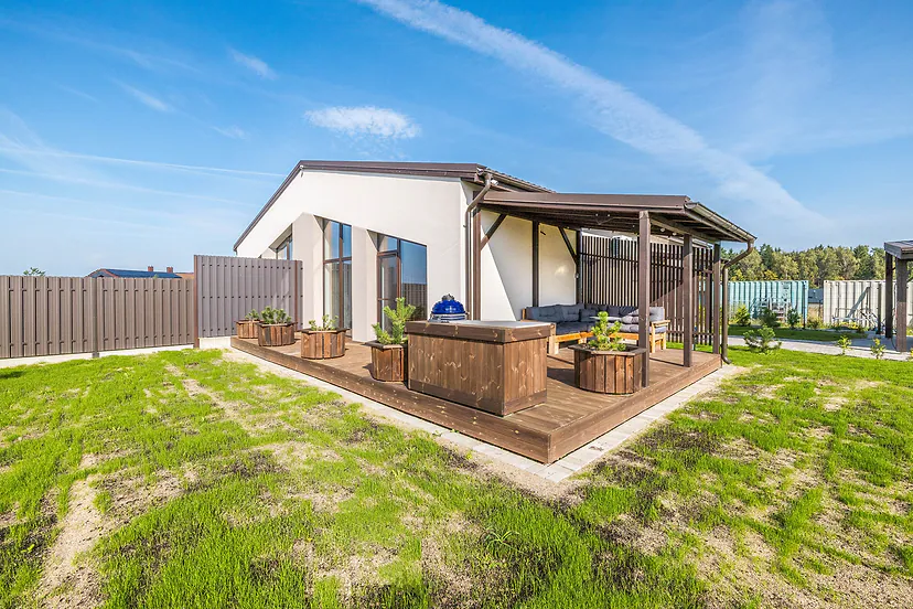 New single-storey house with a wooden deck, a covered terrace and a young lawn