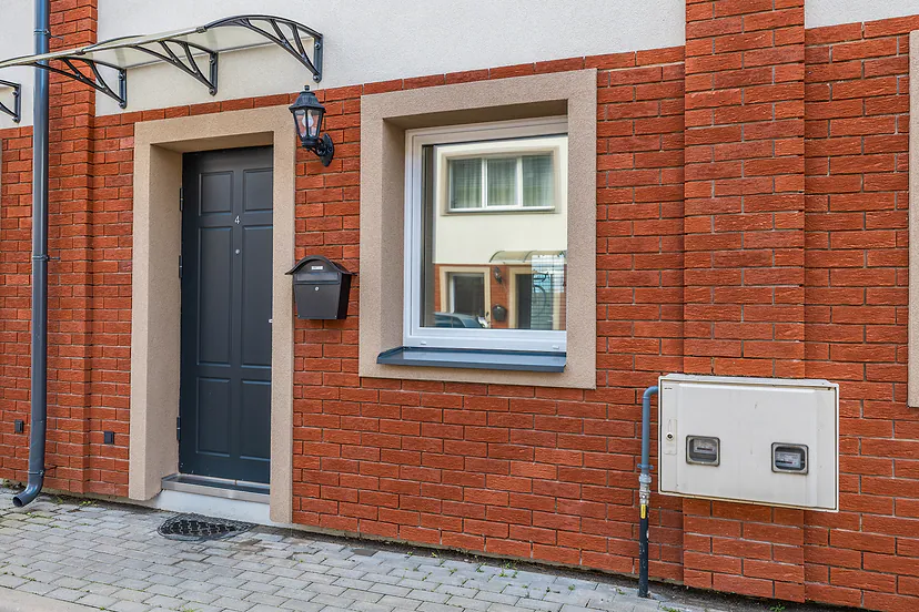 Entrance to a red brick townhouse with a dark door and a lantern