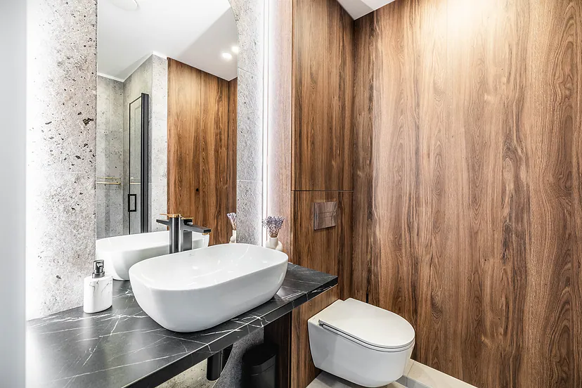 Bathroom with wooden wall panels, speckled stone walls and an oval vessel sink