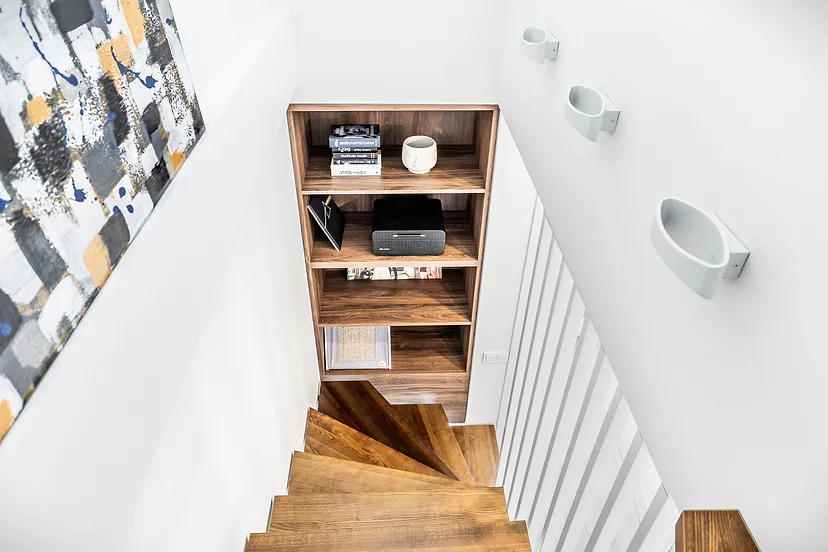 Wooden stairs seen from above, with a shelf and a painting beside them