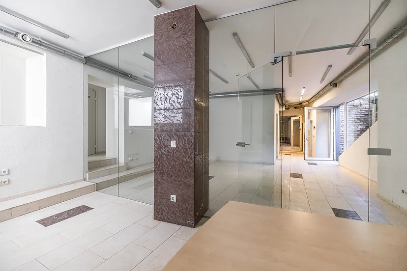 Office corridor with glass-walled rooms and a brown stone column