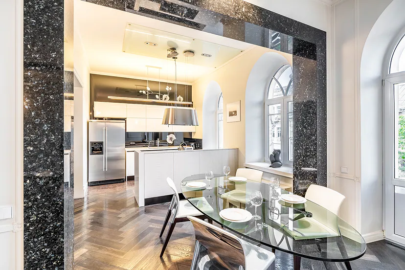 Kitchen and dining area with a glass table, arched windows and a dark stone portal