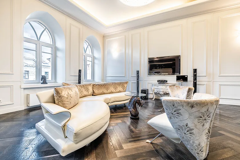 Spacious living room with arched windows, wall moldings and a curved white sofa