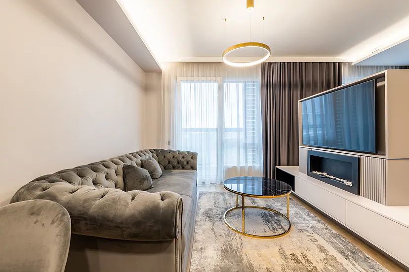 Living room with a velvet sofa, a gold pendant light and a fireplace