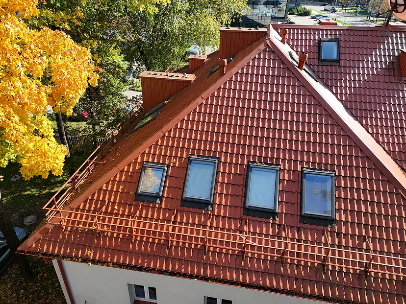 New red roof with skylights and yellow trees in the sun