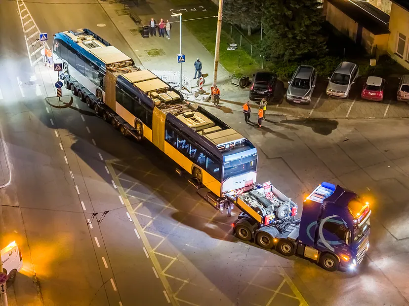 Didelių gabaritų krovinio pervežimas naktį: troleibusas ant platformos sankryžoje
