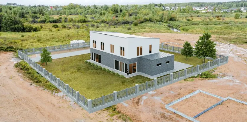 White cube-shaped house in a field with a fence, aerial visualization