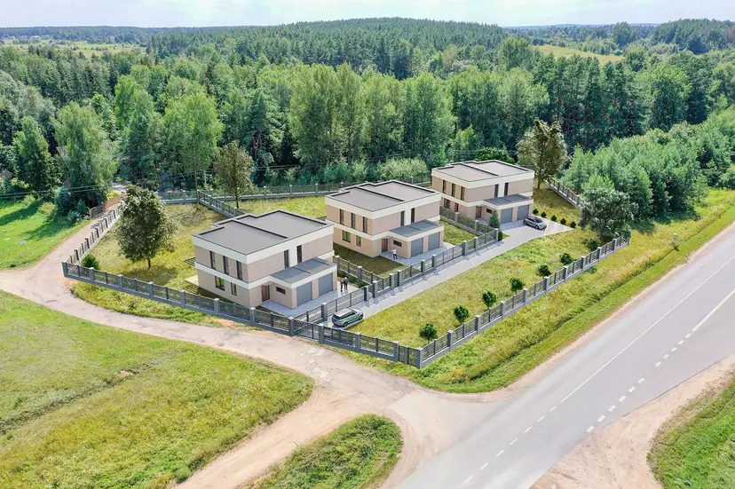 Three new houses by a road and a forest, a visualization placed into an aerial photo