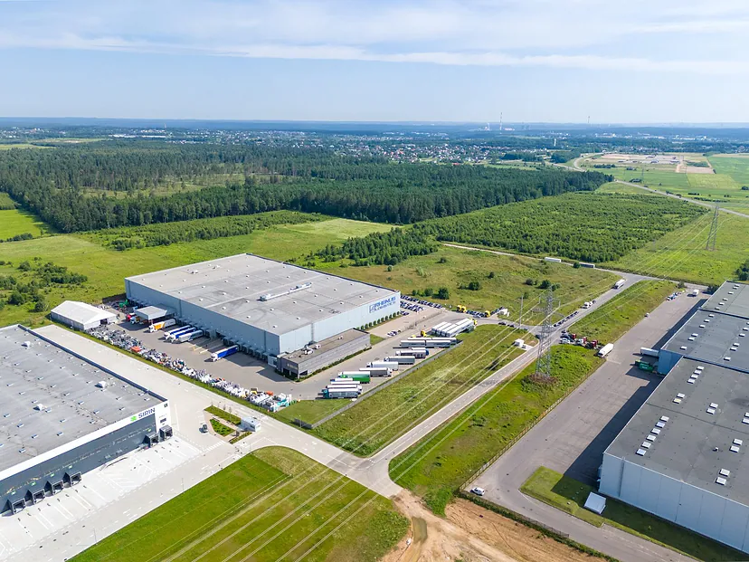 Logistikos sandėliai prie miško, toliau laukai iki horizonto